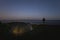 Wild camping with a tent at night in summer. A man stands with a headlamp on the edge of a sea cliff in Paldiski. Starry sky