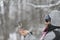 Wild chickadee bird landing on a man`s hands in snowing winter