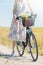 Wild flowers bouquet carried by young woman in dress with flowers in bicycle basket