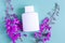 Wild flowers and a white bottle on a colored background. Flowers and cosmetics on a light background