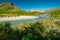 Wild glacial river flows through remote, green Arctic landscape on a sunny day of summer. Njoatsosjahka river and
