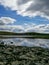 A wild lake with reflections of the clouds and a rocky shoreline