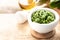 Wild leek pesto with olive oil and parmesan cheese in a white ceramic mortar on a wooden table. Useful properties of ramson. Copy
