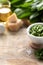 Wild leek pesto with olive oil and parmesan cheese in a white ceramic mortar on a wooden table. Useful properties of ramson. Copy