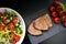 Wild lettuce salad and tomatoes with grilled tuna on a black plate, simple meal concept photography