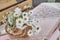 Wild meadow daisies in wicker basket, knitted patchwork tablecloth on table of rural house.