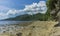 Wild remote untouched beach scene on low tide many corals and rocks visible next to lush jungle and hills in Banda Besar