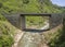 Wild river with muddy water in the Caucasus. Bridge passing over a mountain stream. The rocks are covered with algae, the river is