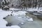 Wild river in winter with old stone arched bridge. Beautiful frosty day. Snowy weather in mountain. Most popular place. Alps