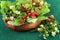 Wild strawberries in wooden bowl on jute fabric background