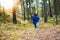 Wild tourism and adventure in real nature concept, blurred figure of woman traveler with big backpack in pine forest