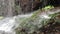 Wild and untamed waterfall in a remote wilderness area, water stream falls from above from a rock onto stones