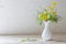 Wildflowers in white vase on background old wall