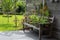 Wildlife friendly suburban garden with rudbeckia hirta flowers, nasturtiums, container pots on wooden bench, and greenery.