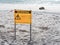 Wildlife warning sign with injured seal on beach