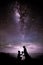 Will you marry me? Silhouette of young man staying on the knee and making proposal for his lovely girl on milky way Background