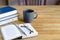 Willow twigs and glasses lie on an open book. On a wooden table is a stack of books and a cup of coffee