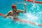 Win. Live portrait of young sportive man, professional swimmer in goggles training at public swimming-pool, outdoors