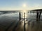 Winchelsea beach landscape view at low tide exposing flat sand with wooden sea groynes protruding from the sand