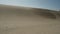 Wind blowing sands from dunes. Backlight