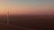 Wind driven generators rotate in rural field at sunset