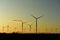 A wind farm of eerie looking turbines in a sunrise