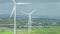 Wind farm in rural area. Wind turbines in green field rotating under stormy sky