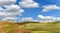 Wind farm turbines white on hill contrast green grass and blue sky, wa