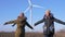 Wind generator, beautiful girlfriends are turning and pointing finger at windmill against sky