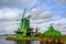 Wind mill in the middle of a green meadow on the waterfront on a beautiful blue day at Zaanse Schans