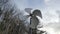 Wind mill slowly turning in the breeze on a winters day, with clouds and forest