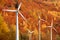 Wind mills power generators against autumn forest