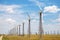 Wind power plant in the field. Wind power station on the horizon, against a beautiful blue sky with clouds. Industry,