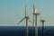 Wind power stations. A row of turbines near the seashore. Wind farm eco field. Eolic park with blue sky in background. Green,