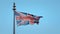 Wind-ragged British Union Jack flag flies in blue sky