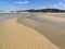 Wind rippled water crosses the sand on the Bushmans River at low tide.