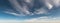 Wind swept clouds float across blue sky panorama