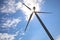 Wind turbine against blue sky, low angle view. Alternative energy source