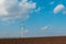 Wind turbine in agricultural field, windmill generating green energy. Background of blue sky. Fertile soil land.