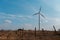 Wind turbine in agricultural vineyard field, windmill generating green energy. Background of blue sky.