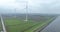 Wind turbine along a dyke. WInd energy power electricity sustainable energy generation. Windmill, wind, water grass