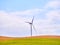 Wind turbine between an arid field and a blue sky background for copy space