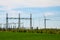 Wind turbine farm and substation electricity power transmission lines in landscape with green grass and blue sky