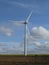 Wind turbine in a field with cottony clouds in the background