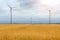 Wind turbine among golden ears of grain crops