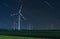 Wind turbine on green fields at night. Natural wind power plants and sustainable eco-friendly energy