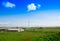 Wind turbine near a farm in a valley with blue sky
