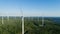 Wind turbine near green forest, beautiful aerial landscape with blue sky. Producing energy in environmentally friendly way.