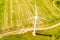 Wind turbine near path in farmland, aerial landscape. Renewable energy concept