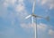 Wind turbine producing alternative energy on cloudy sky background